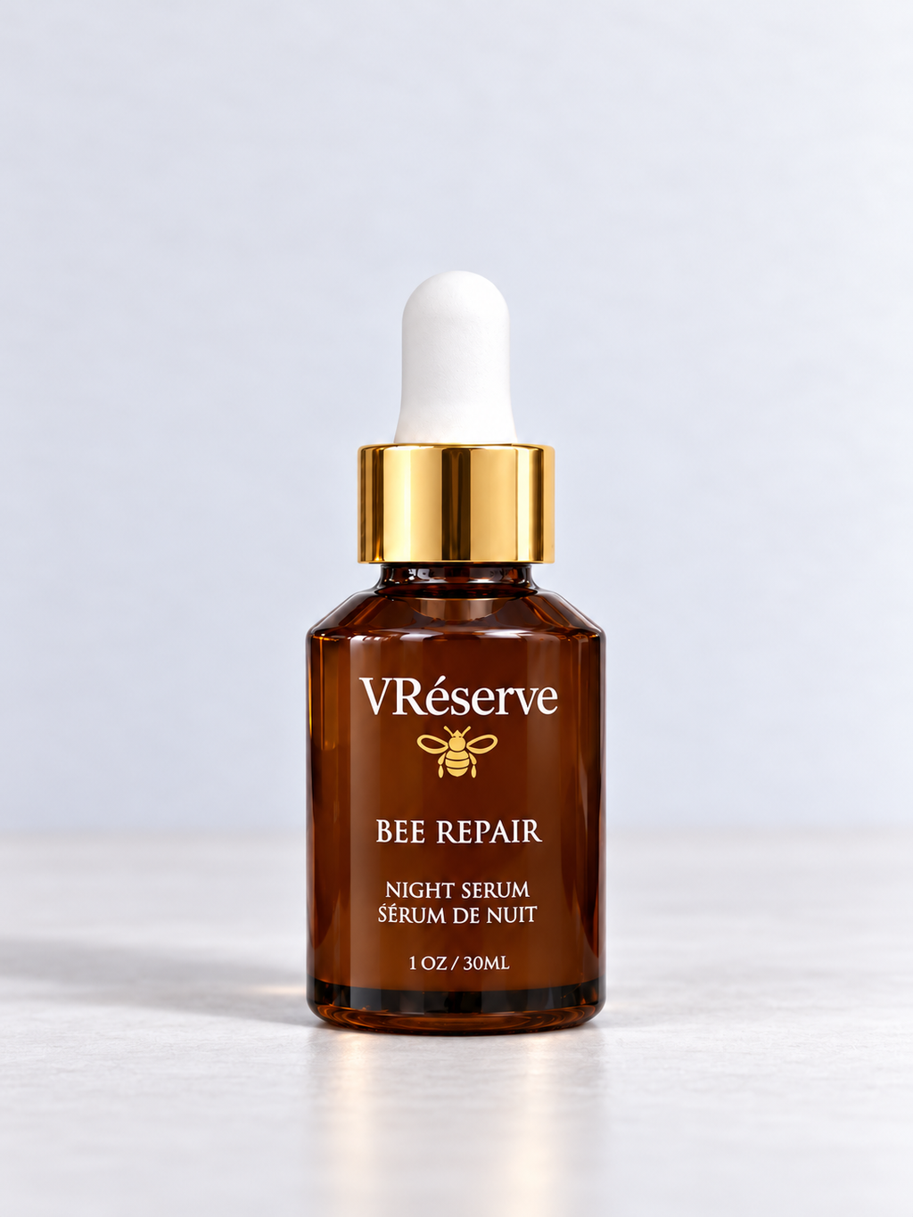 VReserve Bee Repair Night Serum in a 1 oz amber glass dropper bottle with a gold collar and white dropper cap, set against a clean light gray background.