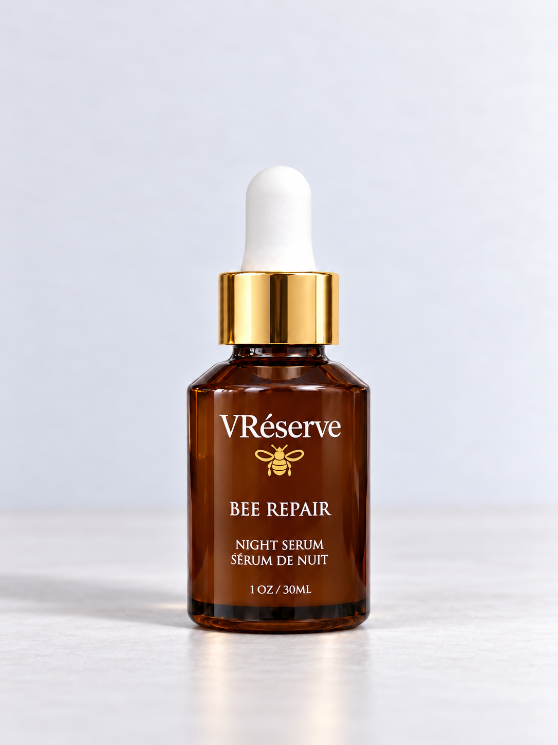 VReserve Bee Repair Night Serum in a 1 oz amber glass dropper bottle with a gold collar and white dropper cap, set against a clean light gray background.