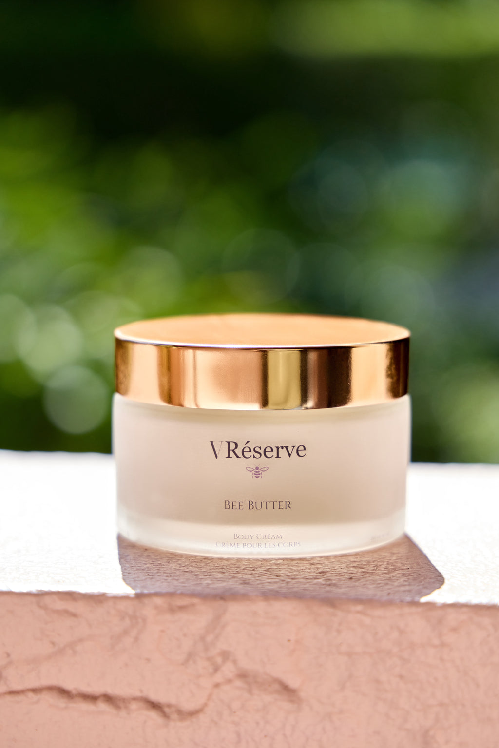 VRESERVE BEE BUTTER resting on white stone. 