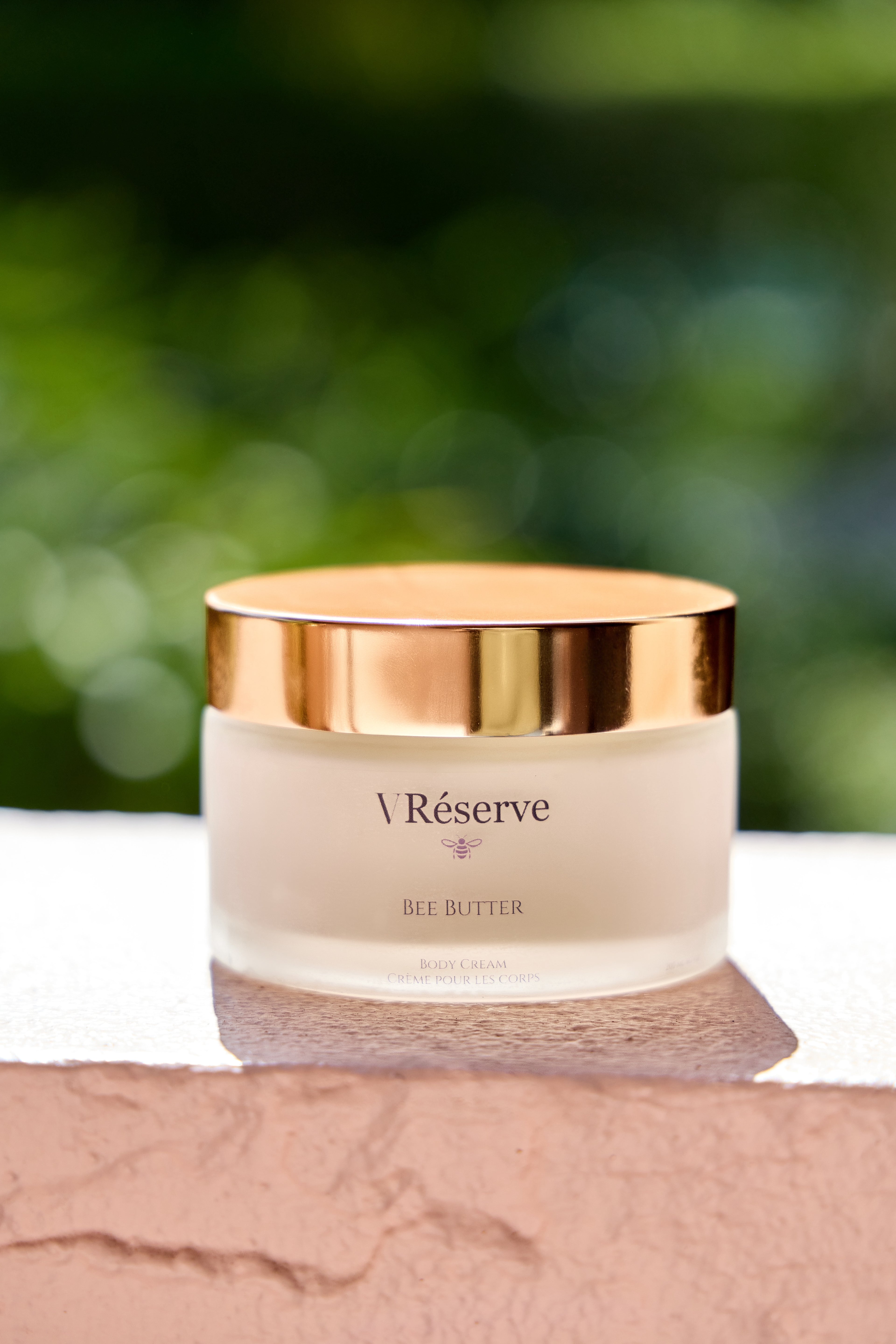 VRESERVE BEE BUTTER resting on white stone. 