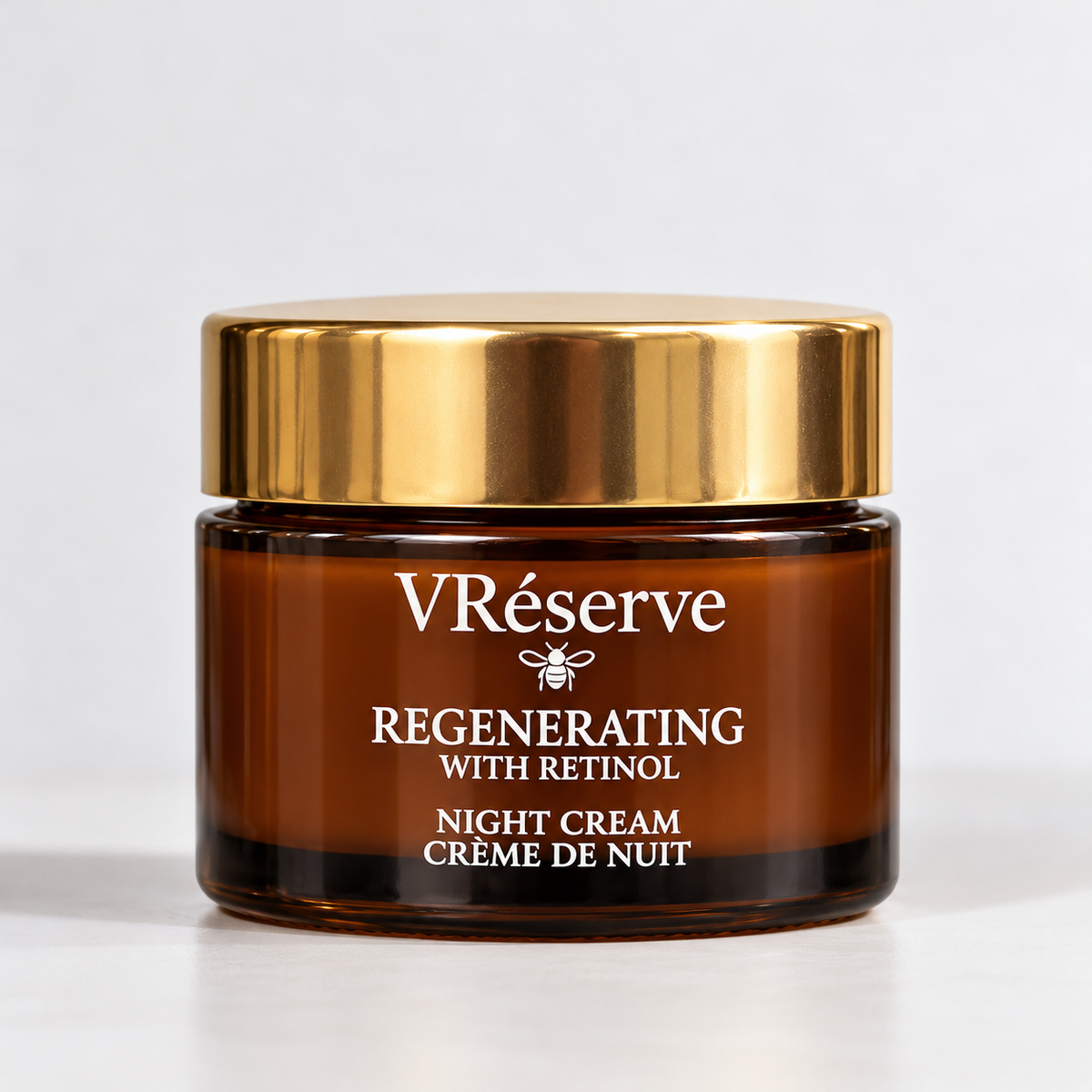 A jar of VRéserve Regenerating with Retinol Night Cream, featuring an amber brown glass container and a shiny gold lid, set against a clean white background.