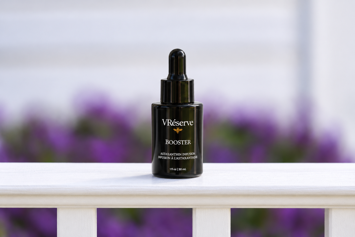 VRéserve Astaxanthin Booster on white fence with purple flowers behind.